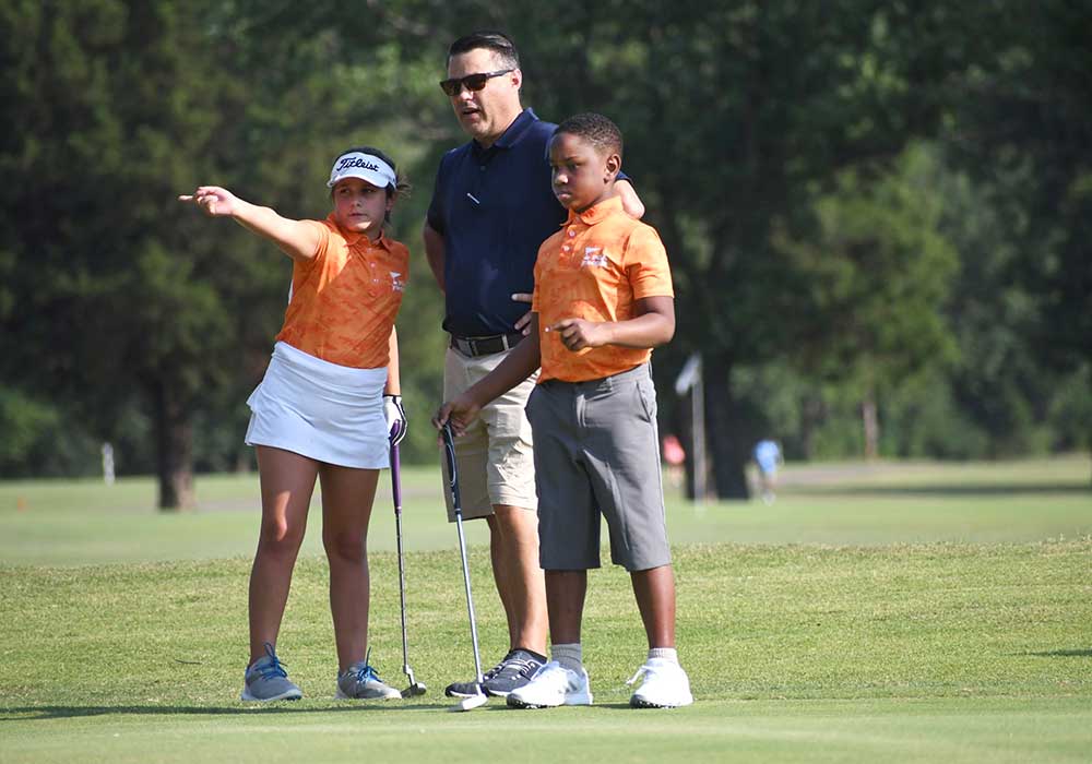 Golf instructor with two youth golfers.