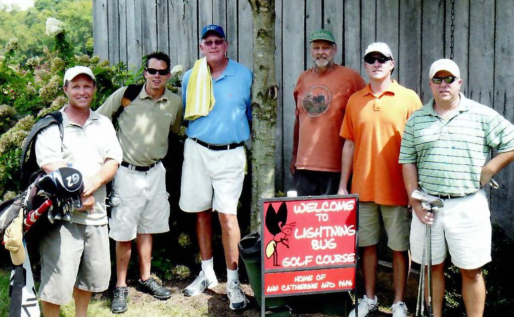 Six golfers standing by Welcome to Lightning Bug Golf Course sign.
